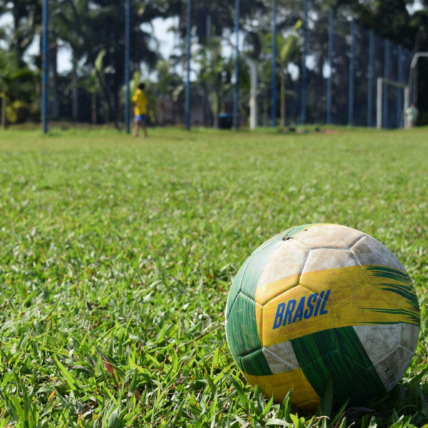 Bola de futebol branca, verde e amarela com a escrita “Brasil”, em um campo de futebol